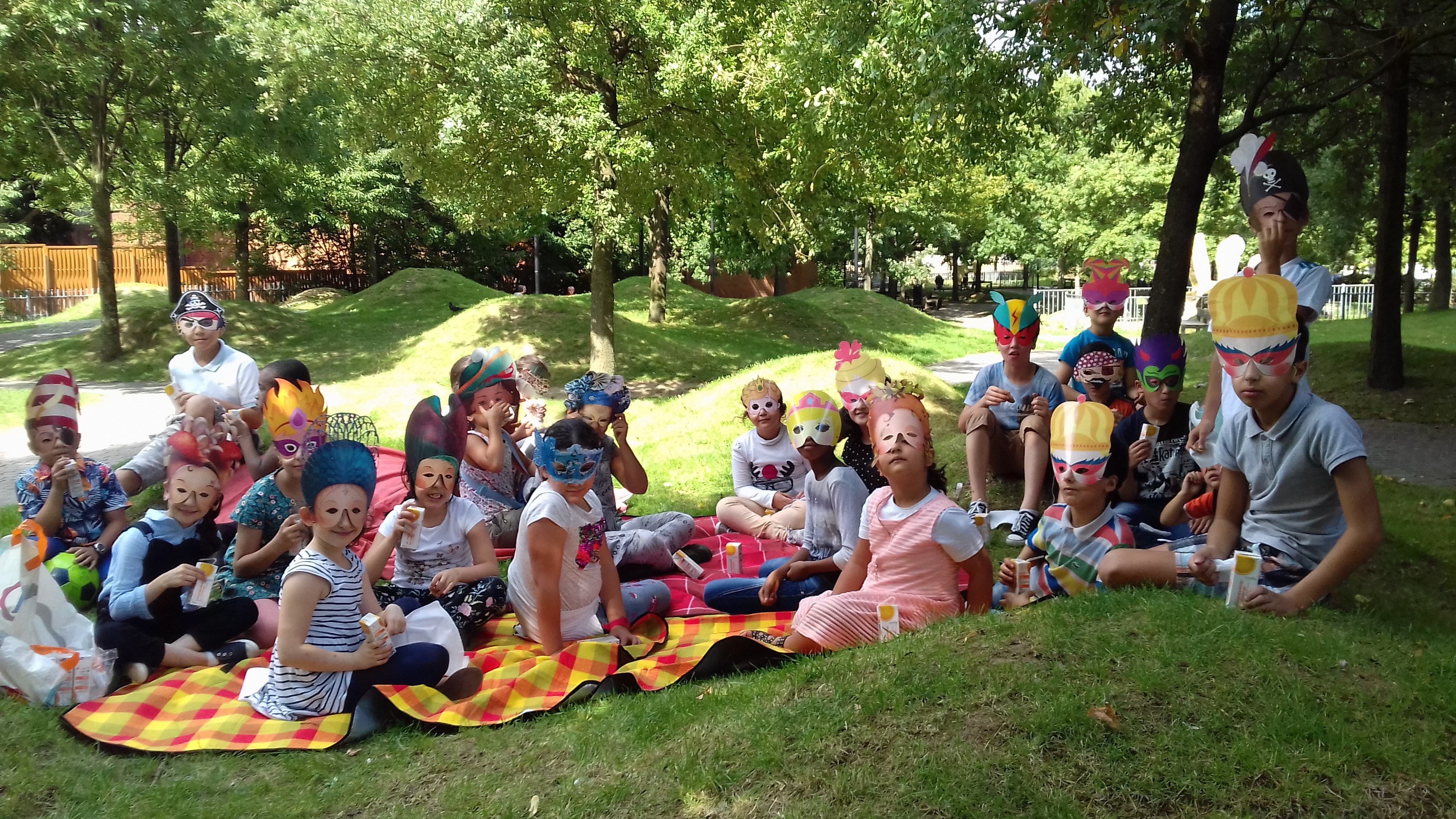 De nombreux enfants masqués regardent l'appareil photo, assis dans la nature
